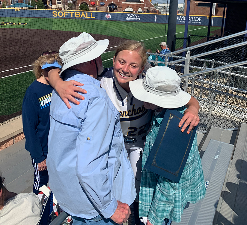 Pitcher Kylee Lynch hugs donors Larry and Leah Westmoreland
