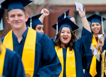 Happy female graduate raising up arms cheering during walk into Graduation ceremony